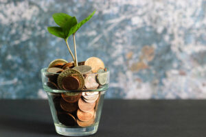 clear glass filled with pennies with a plant sprouting out of it